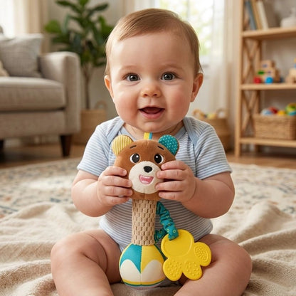 Bébé assis sur un tapis tenant un hochet peluche coloré à anneaux jaunes