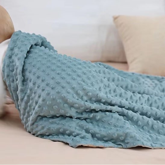 Bébé emmailloté dans une couverture tricot relief pois bleu-vert ultra-douce effet cocooning