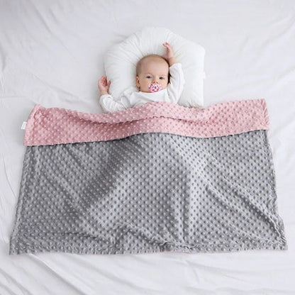 Nouveau-né allongé sur une couverture bébé tricot rose et grise personnalisée avec prénom brodé