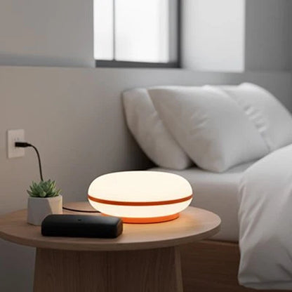 Lampe de chevet design ovale blanche et orange près du lit