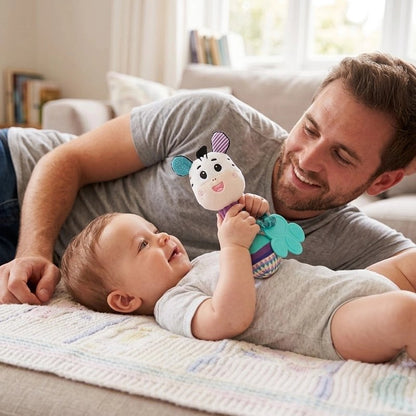 Papa allongé près de son bébé éveillé qui tient un hochet peluche animal