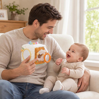 Papa assis avec son bébé qui découvre les faces illustrées d'un cube d'activité